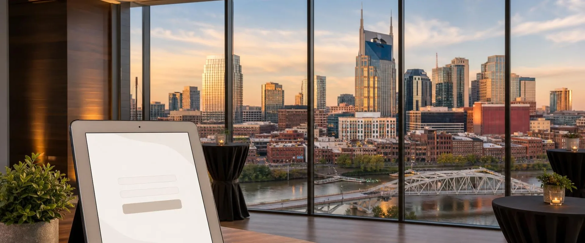 Silver iPad tablet in a Nashville high-rise event space with the AT&T Building and the Cumberland River